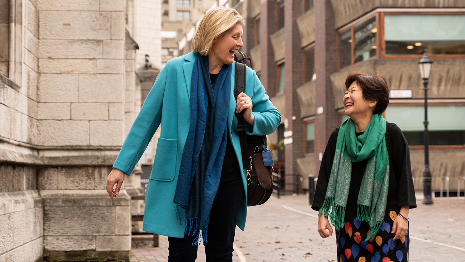 ACO Principal Violin Helena Rathbone walks beside ACO Violin Aiko Goto and they are laughing and happy.