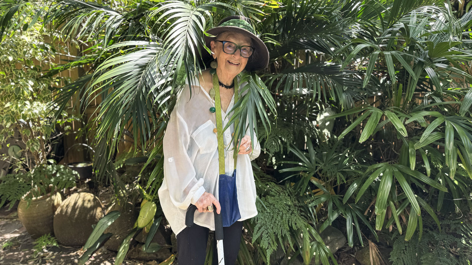 ACO Subscriber Norma Disher Hawkins stands in her garden next to a fern